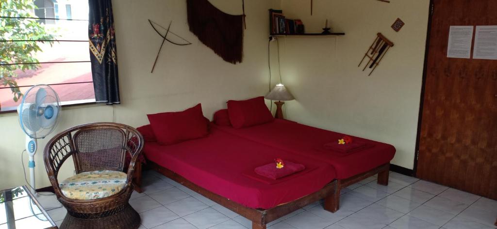 a bedroom with a red bed with a chair and a window at Homestay Galpera Papua in Jayapura