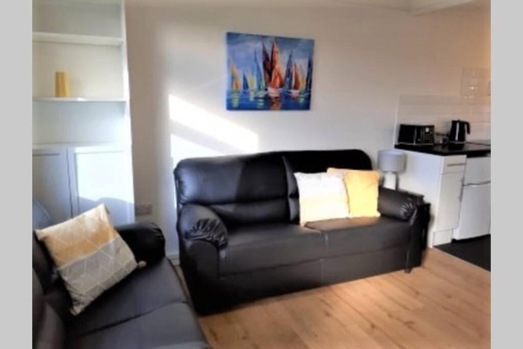 a living room with a black leather couch and a kitchen at Exceptional Chalet near to Beach, Broads & Gt Yarmouth in Great Yarmouth