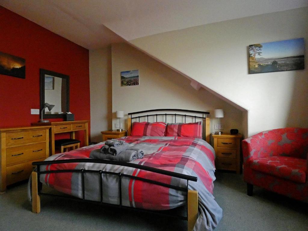 a bedroom with a bed with red walls and a chair at Bryn Melyn Apartments in Barmouth