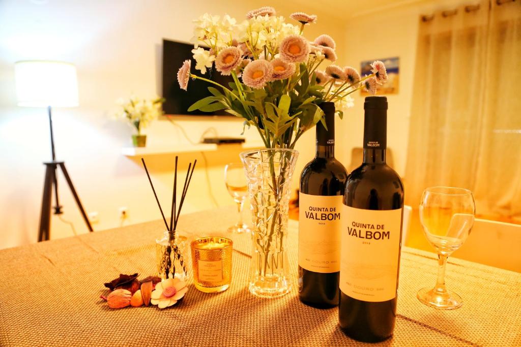 duas garrafas de vinho sentadas numa mesa com flores em Bom dia Parque Nações LisboaZ em Lisboa