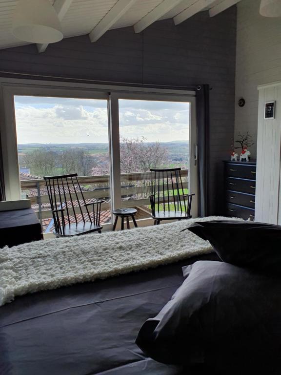 a bedroom with a bed and a large window with chairs at Chalet de la Sablière in Amougies