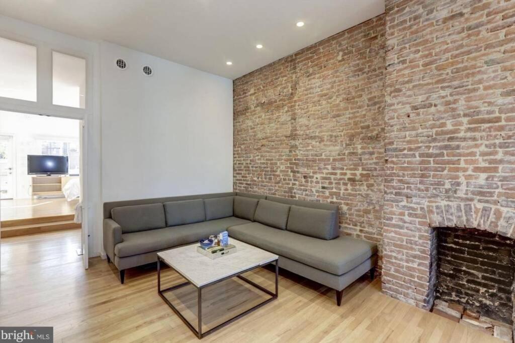 a living room with a couch and a brick wall at Lofty DC Sanctuary in Washington