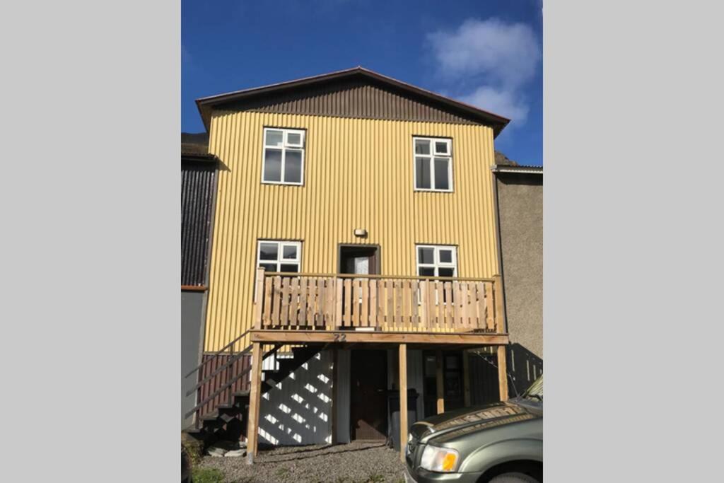 a large yellow house with a balcony and a car at House with a warm soul in North Iceland in Siglufjörður