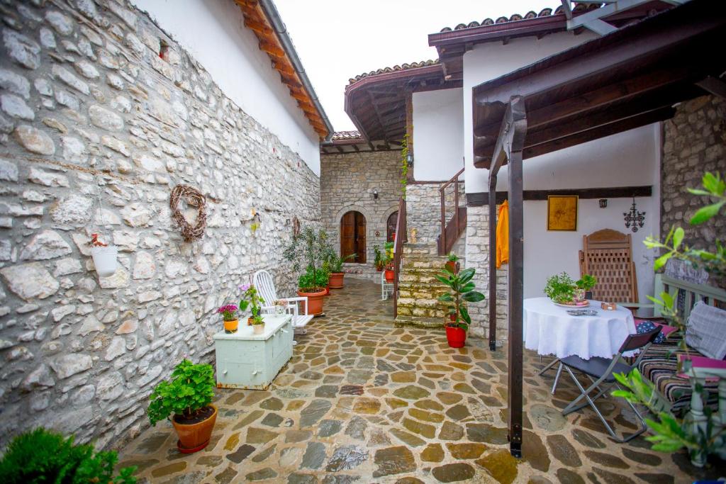 un patio de un edificio con una mesa y macetas en Bujtina Kodiket Guesthouse en Berat
