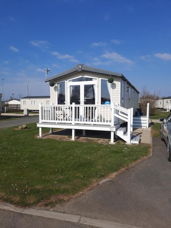 a small white house with a porch and a fence at Church Farm Haven Holiday Park in Pagham