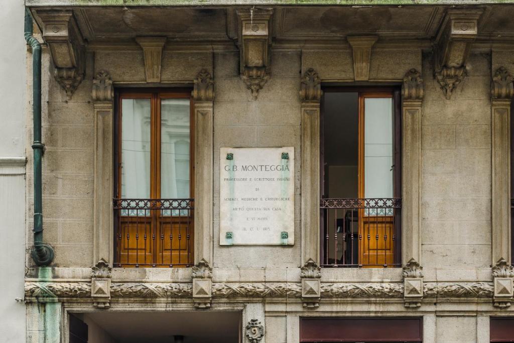 un bâtiment avec trois fenêtres et un panneau sur celui-ci dans l'établissement Ca' Monteggia Guest House, à Milan