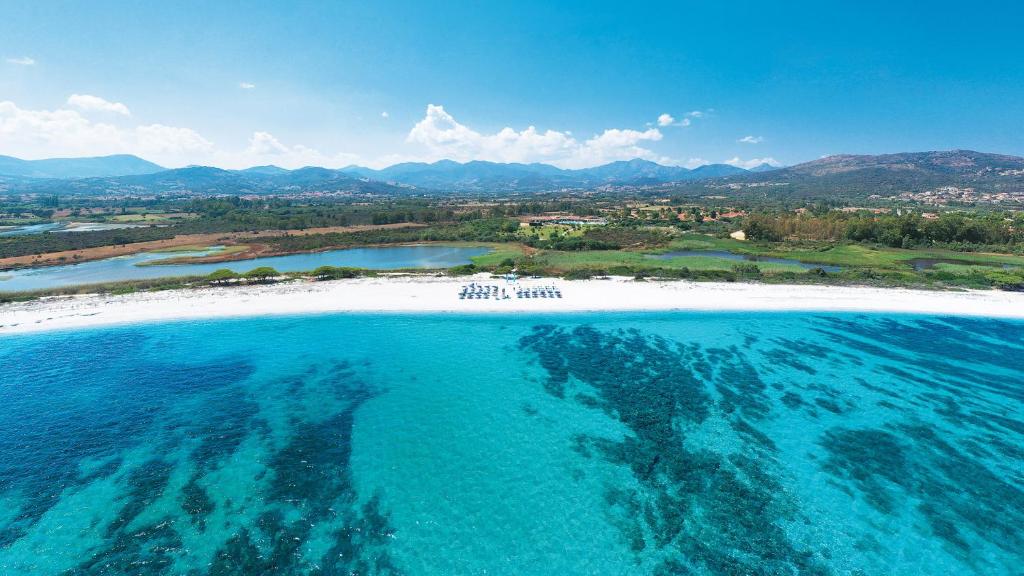 eine Luftansicht auf einen Strand mit blauem Wasser in der Unterkunft Amareclub Janna e Sole Resort in Budoni