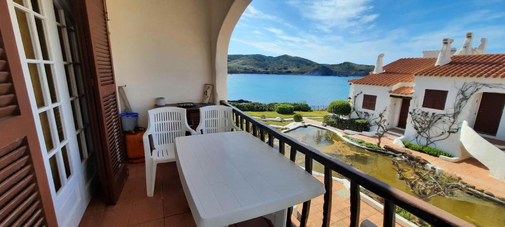 uma varanda com uma mesa e vista para a água em Homenfun Menorca Playa de Fornells II em Fornells