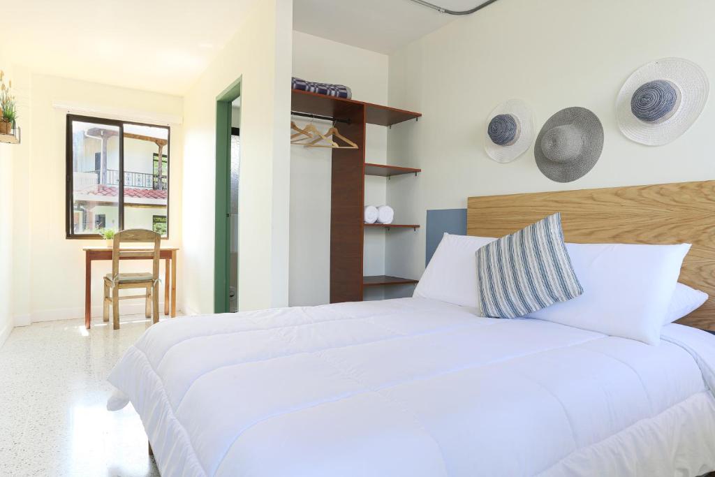 a bedroom with a large white bed and a table at Soy Local Guatape in Guatapé