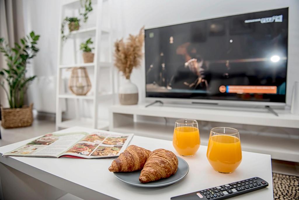 a table with two glasses of orange juice and croissants at Apartamenty Rejtana in Leszno