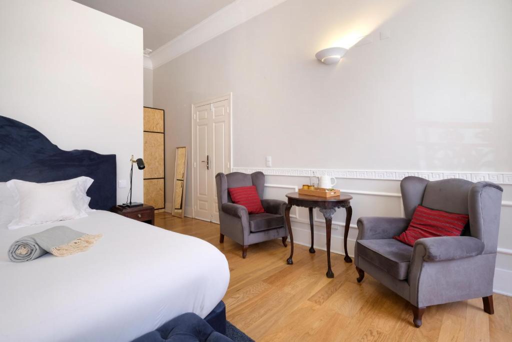 a bedroom with a bed and two chairs and a table at 1869 Príncipe Real House in Lisbon