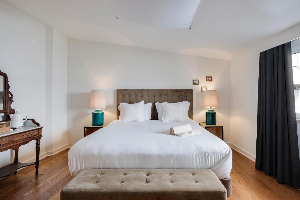a bedroom with a large white bed and a table at 1869 Príncipe Real House in Lisbon
