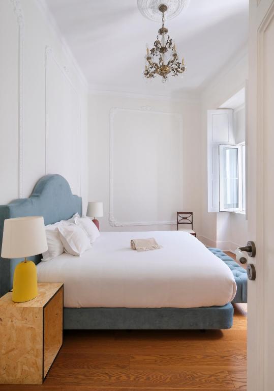 a bedroom with a large white bed and a lamp at 1869 Príncipe Real House in Lisbon