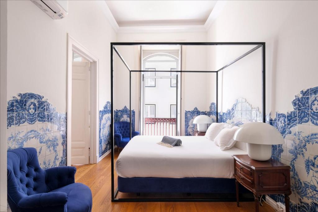 ein Schlafzimmer mit einem großen Bett und blauen Stühlen in der Unterkunft 1869 Príncipe Real House in Lissabon