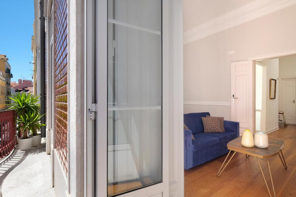 a living room with a blue couch and a glass door at 1869 Príncipe Real House in Lisbon