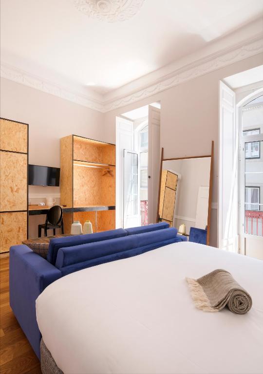 a bedroom with a white bed and a blue couch at 1869 Príncipe Real House in Lisbon