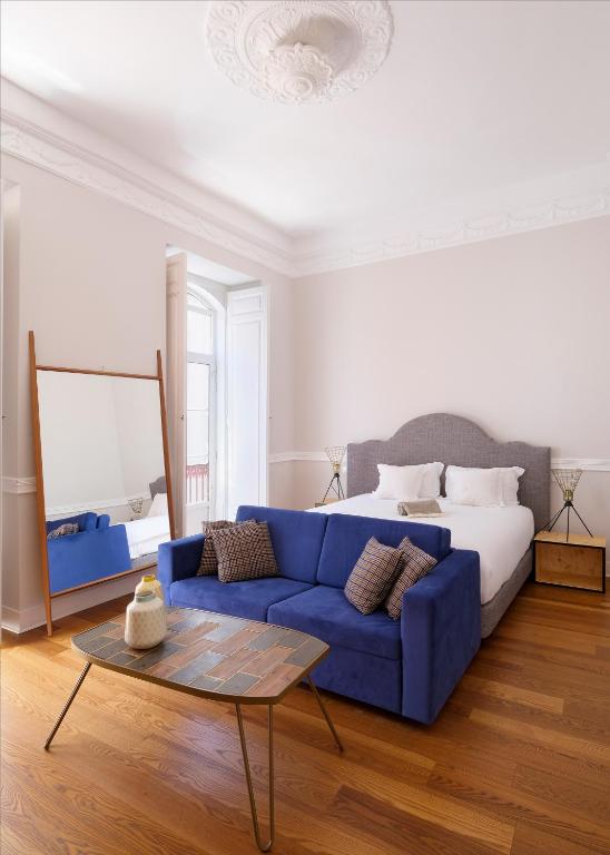 a living room with a blue couch and a bed at 1869 Príncipe Real House in Lisbon