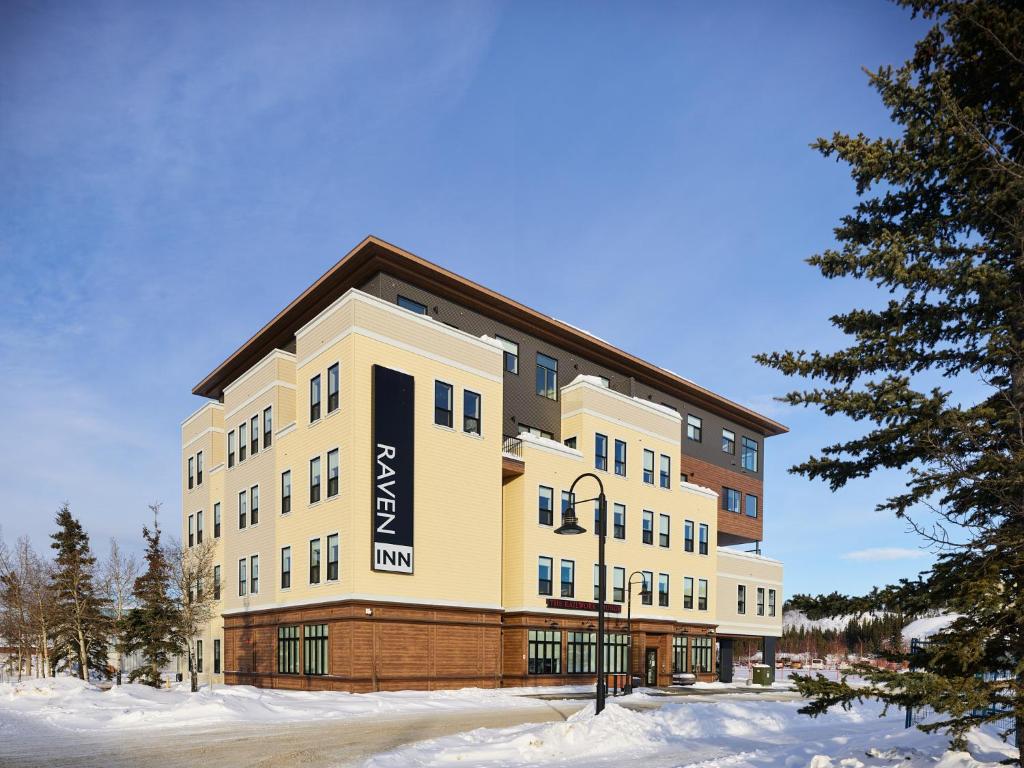 a large building with a sign on it in the snow at Raven Inn Whitehorse in Whitehorse