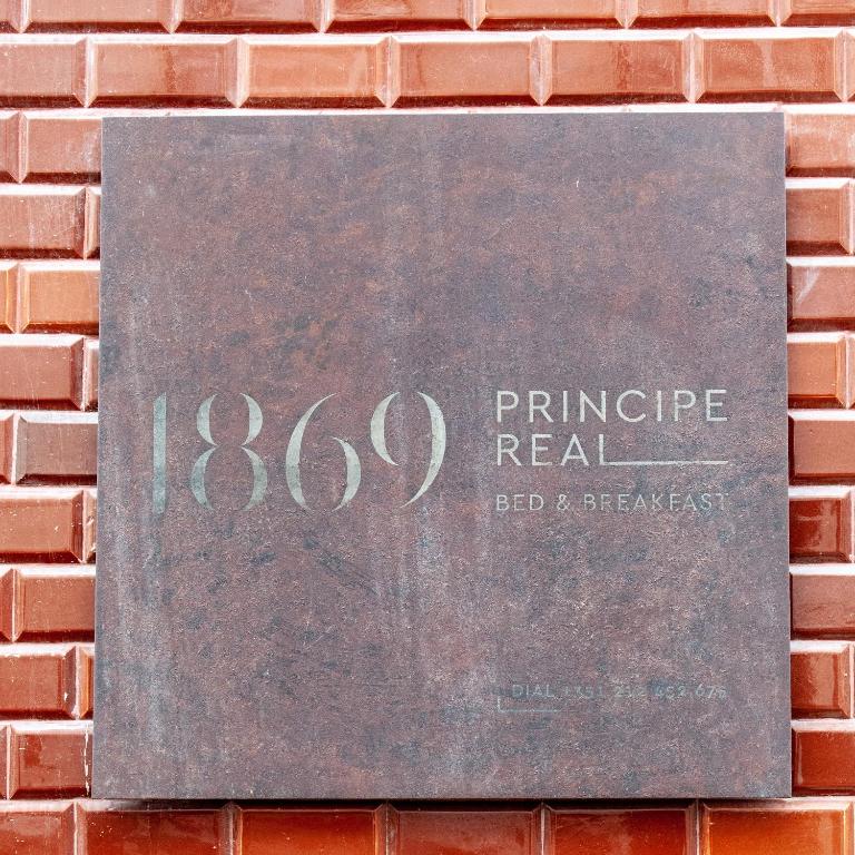 a sign on the side of a brick wall at 1869 Príncipe Real House in Lisbon
