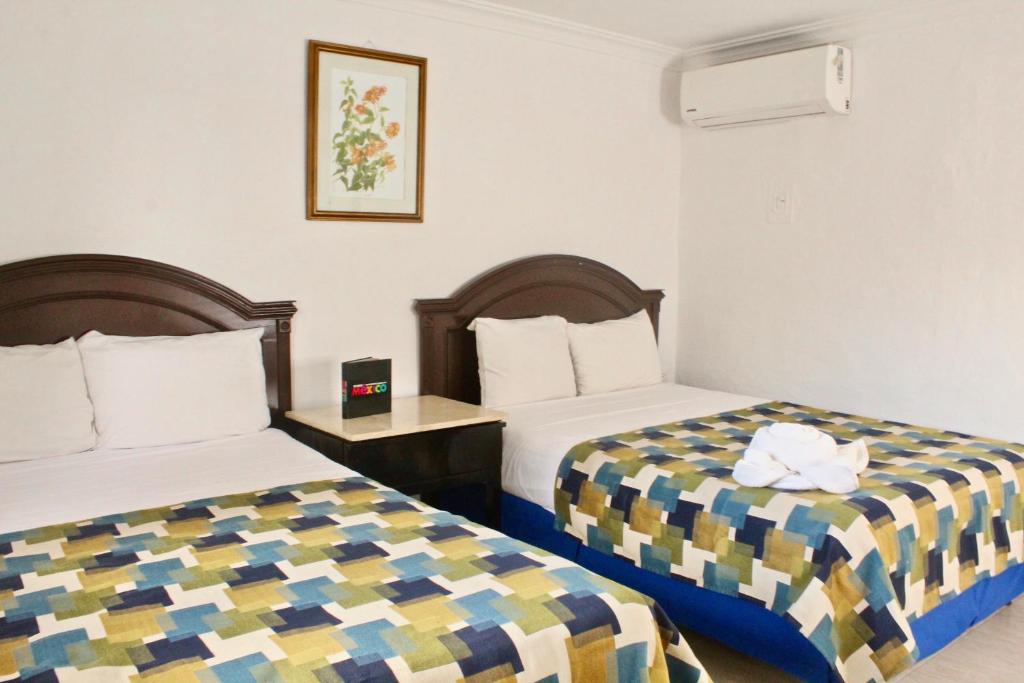 una habitación de hotel con 2 camas en una habitación en Hotel El Cid en Mérida