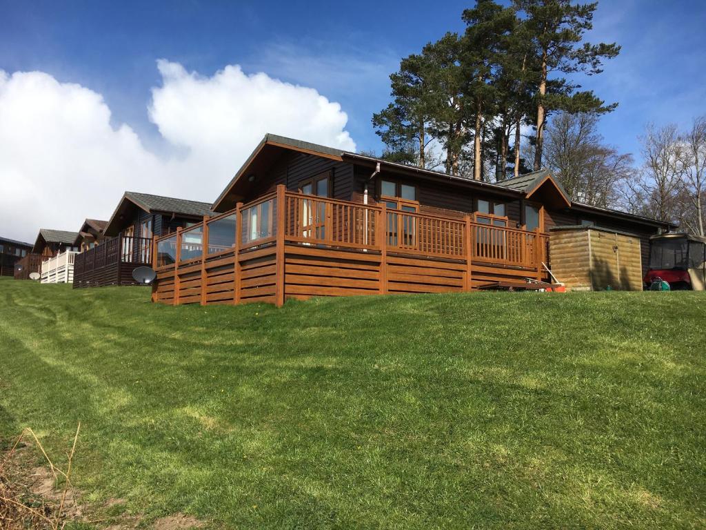 una casa de madera con una gran terraza en una colina en Millie,s View 18 hole free Golf, en Swarland