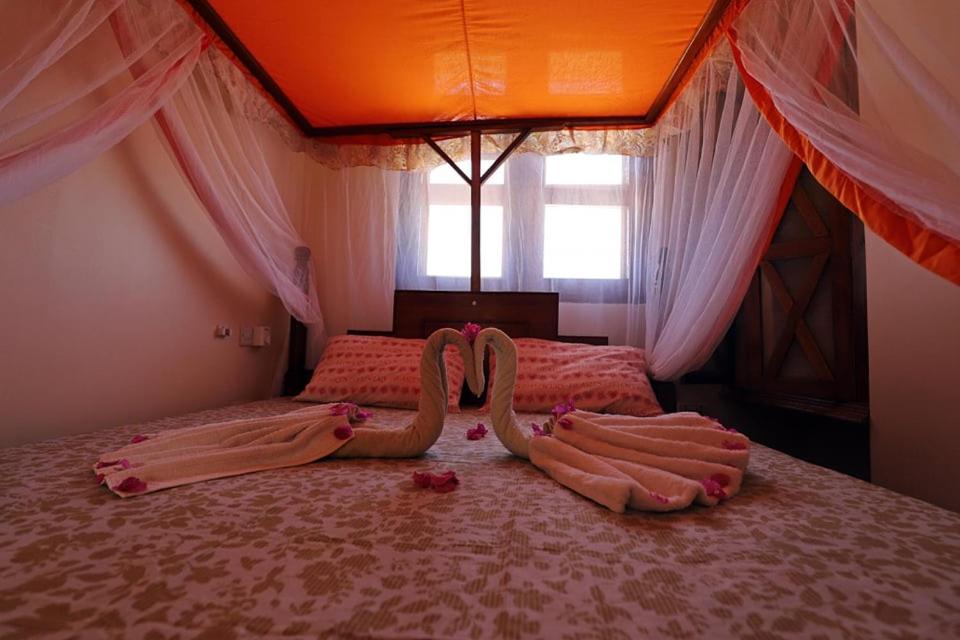 un dormitorio con dos cisnes hechos de sangre en una cama en Triton Apartments en Pwani Mchangani