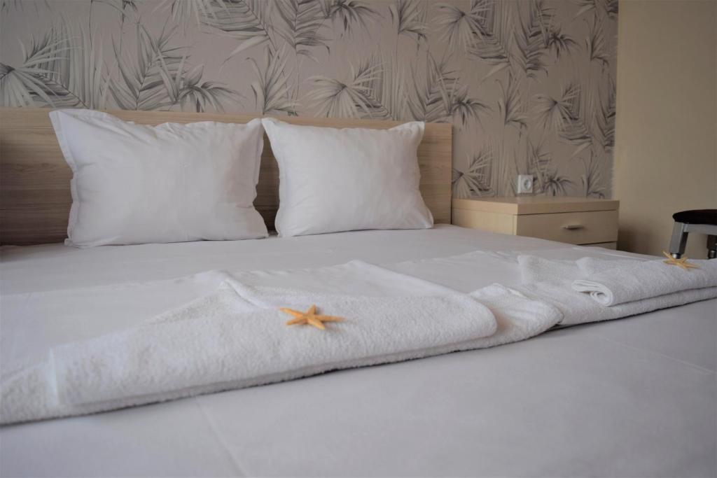 a white bed with white pillows and a towel on it at Guest House Gloria in Nesebar