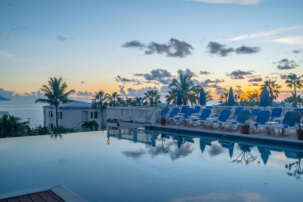 a pool with chairs and a sunset in the background at La Vista Resort in Simpson Bay