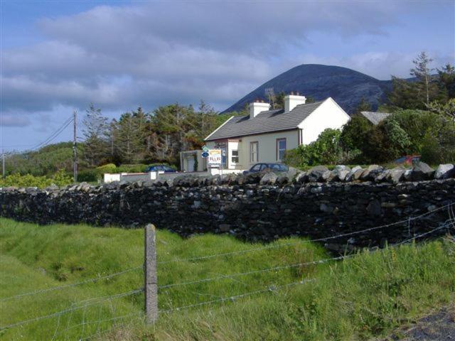 una casa detrás de una pared de piedra en un campo en Achill View B&B en Murrisk