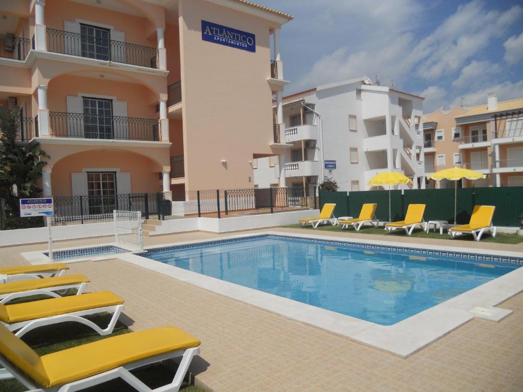 una piscina con sillas y un edificio en Apartamentos Atlantico by OA en Albufeira