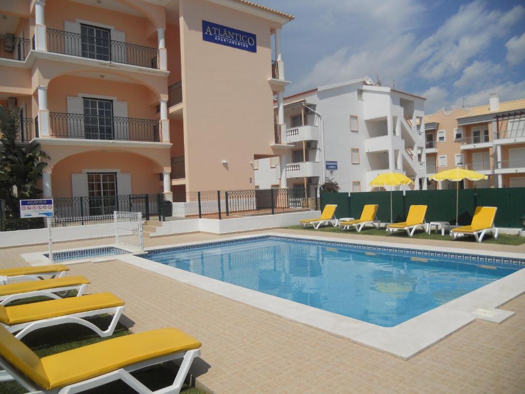 a swimming pool with chairs and a building at Apartamentos Atlantico by OA in Albufeira