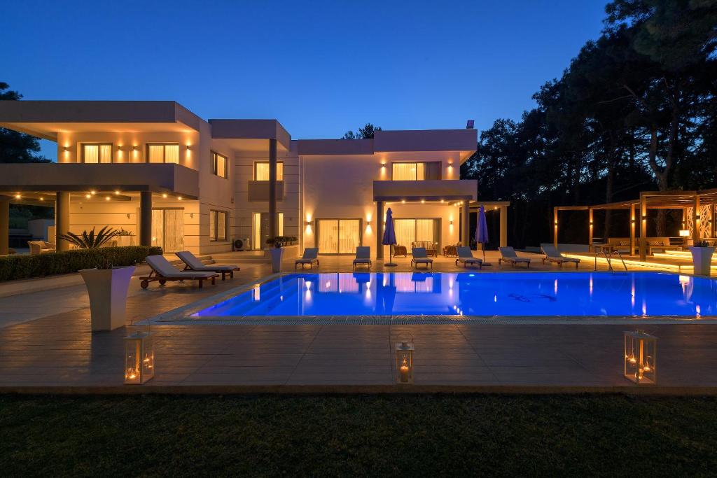 een groot huis met een zwembad in de nacht bij Bella Foresta Villa in Ialyssos
