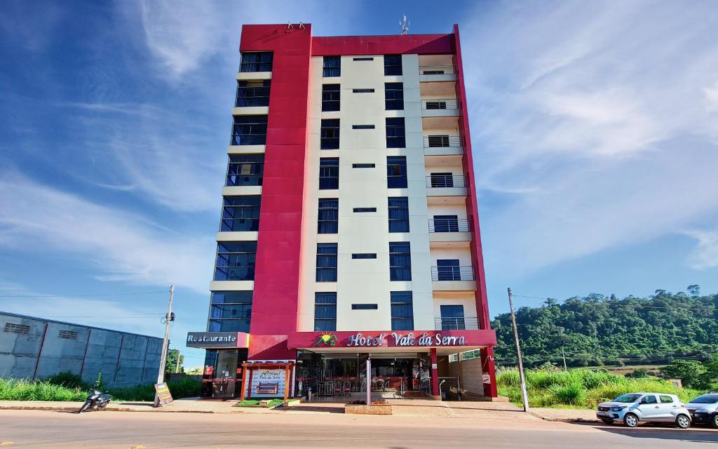 a tall red and white building with a store at Hotel Vale da Serra in Parauapebas