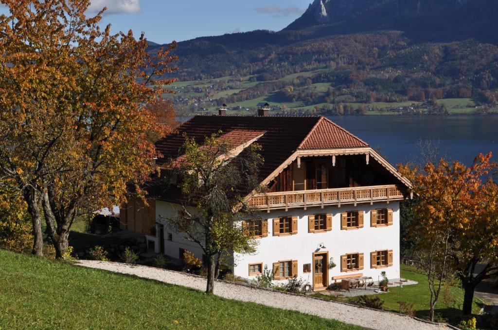 a large white house on a hill with a lake at Exklusiv Apartment Scheichl in Unterach am Attersee