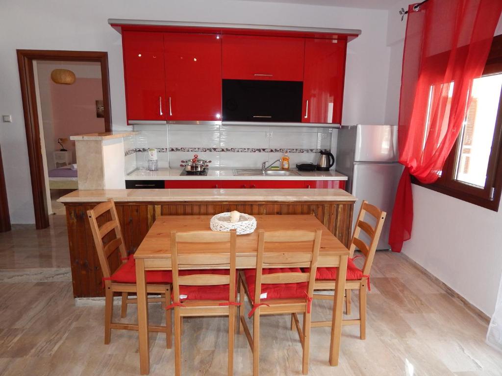 eine Küche mit einem Holztisch und roten Schränken in der Unterkunft Palm House Nikiti - Apartments Vicky in Nikiti
