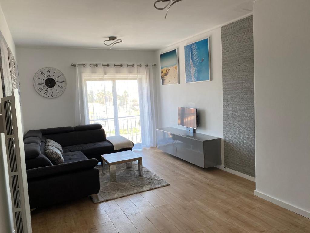 ein Wohnzimmer mit einem schwarzen Sofa und einem TV in der Unterkunft Appartement à Esmoriz de 3 pièces - 72m2 in Esmoriz