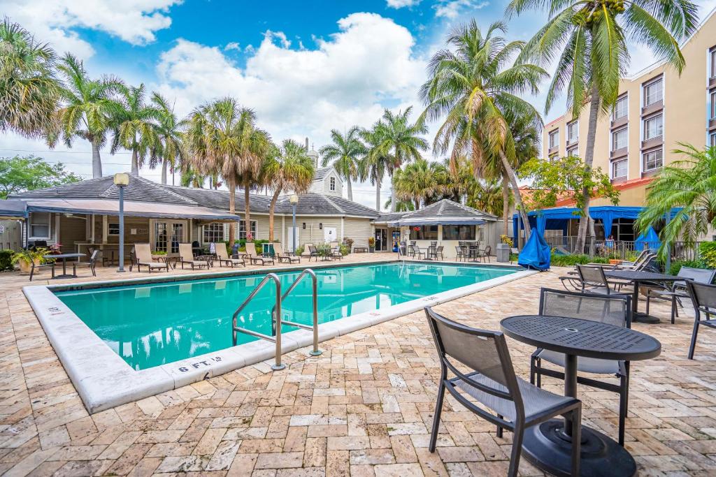 a swimming pool with tables and chairs and palm trees at Hotolos Hollywood in Hollywood