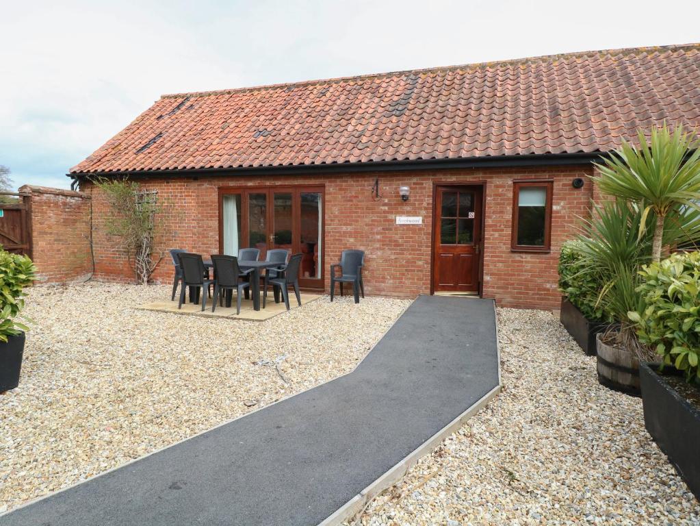 a brick house with a pathway leading to a patio at Beechwood in Wood Norton