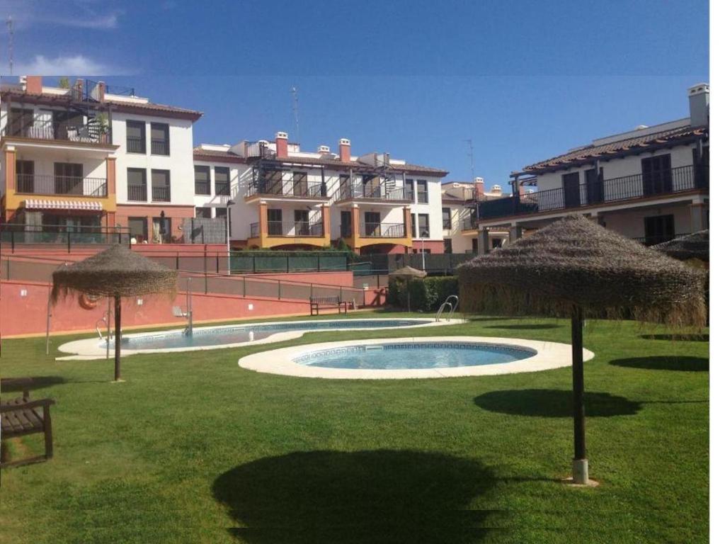 un patio con piscina y sombrillas en Costa Esuri Golf y Playa V, en Ayamonte