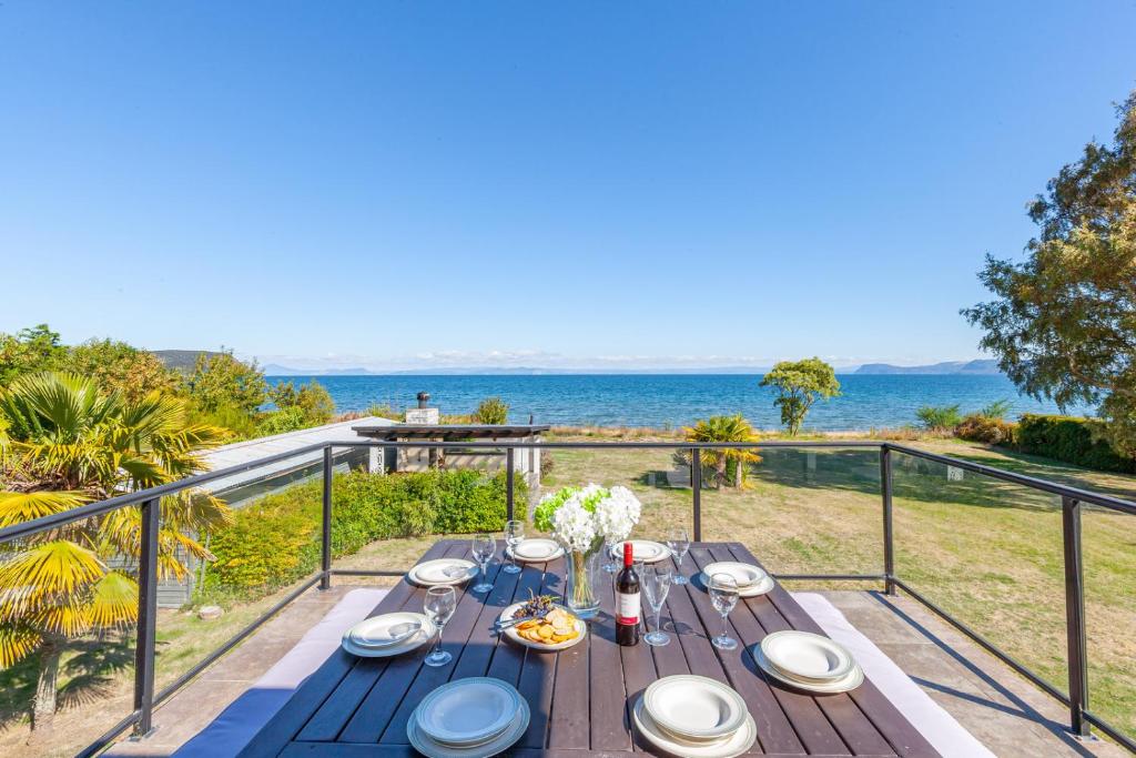 een tafel op een balkon met uitzicht op de oceaan bij Lakefront Villa - Waitahanui Holiday Home in Waitahanui