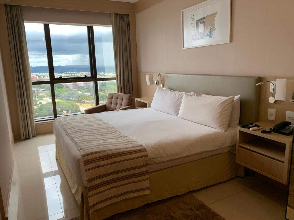 a hotel room with a bed and a large window at Localização incrível vista ótima equipado e novo in Brasília