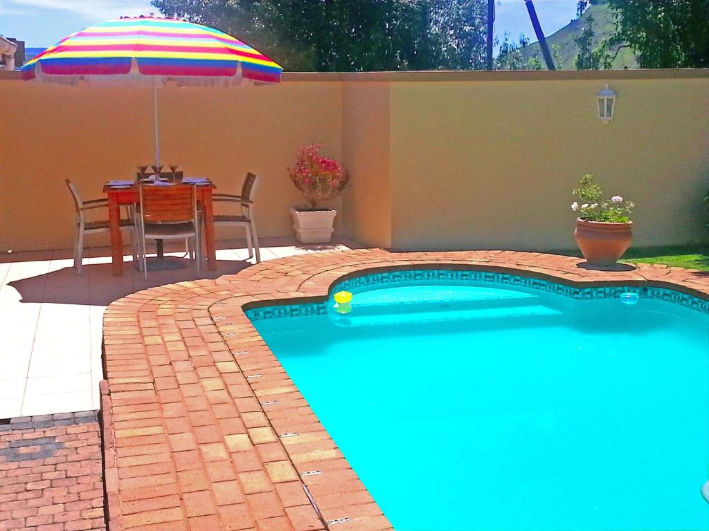 a swimming pool with a table and an umbrella at Majestic in Kokstad