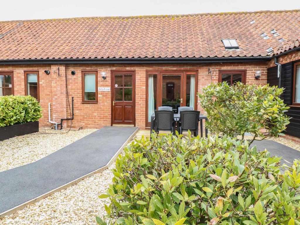 a brick house with a patio and chairs in front of it at Holly Berry in Wood Norton