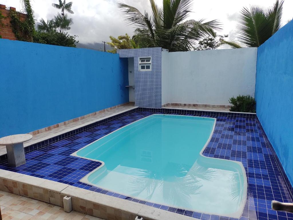einen Pool mit blauer Wand und blauem Fliesenboden in der Unterkunft Home beach Massaguaçu 100 mt da praia in Caraguatatuba