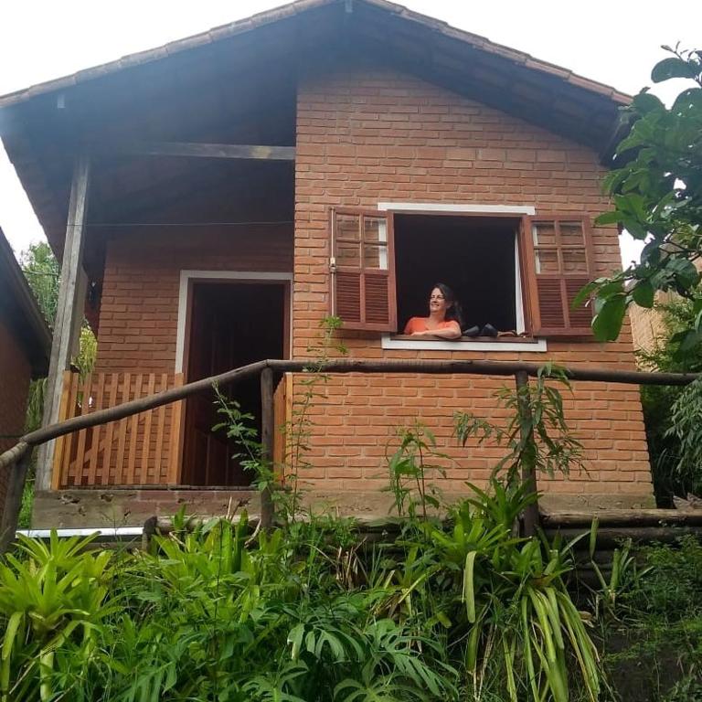 a woman looking out of a window of a house at O Chalé de Rita in Lima Duarte