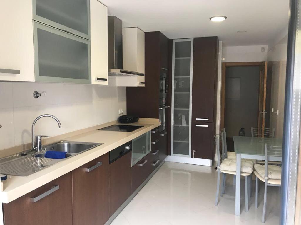 a kitchen with wooden cabinets and a sink and a table at Luxury ApartHotel Colinas do Cruzeiro in Odivelas