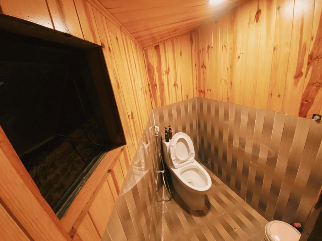 a bathroom with a toilet in a wooden room at EUDORA HOUSE 2 in Da Thien