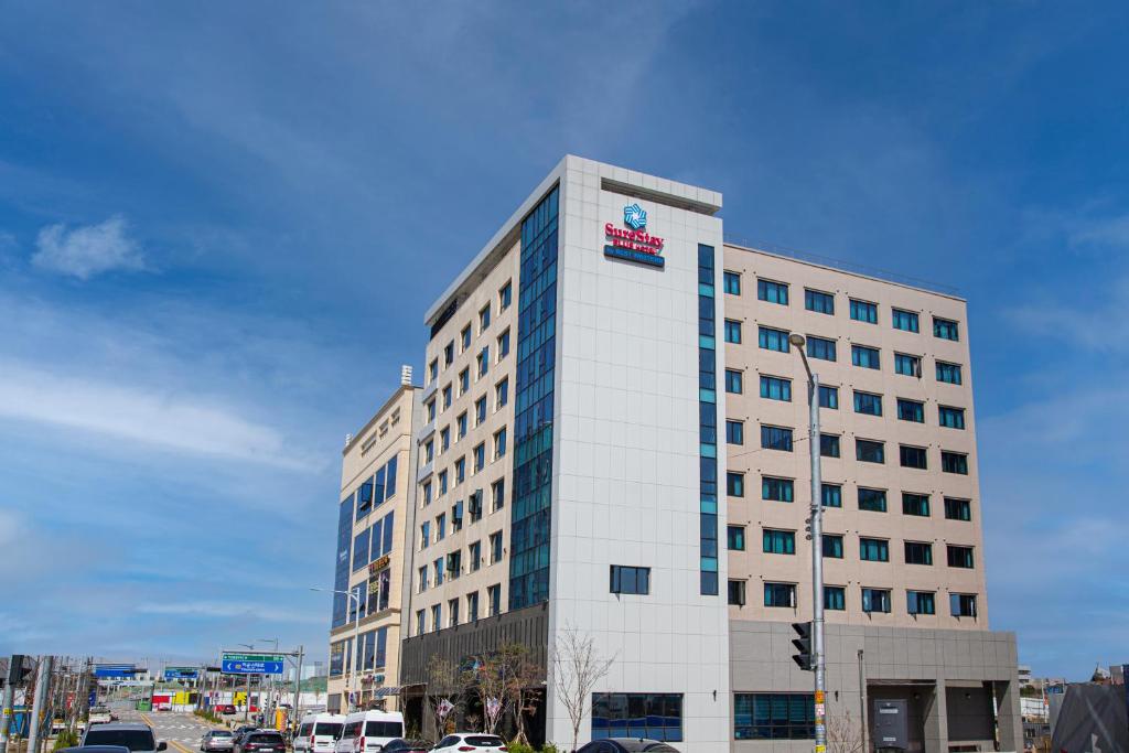 a tall white building with a clock on it at SureStay Plus Hotel by Best Western Asan in Asan