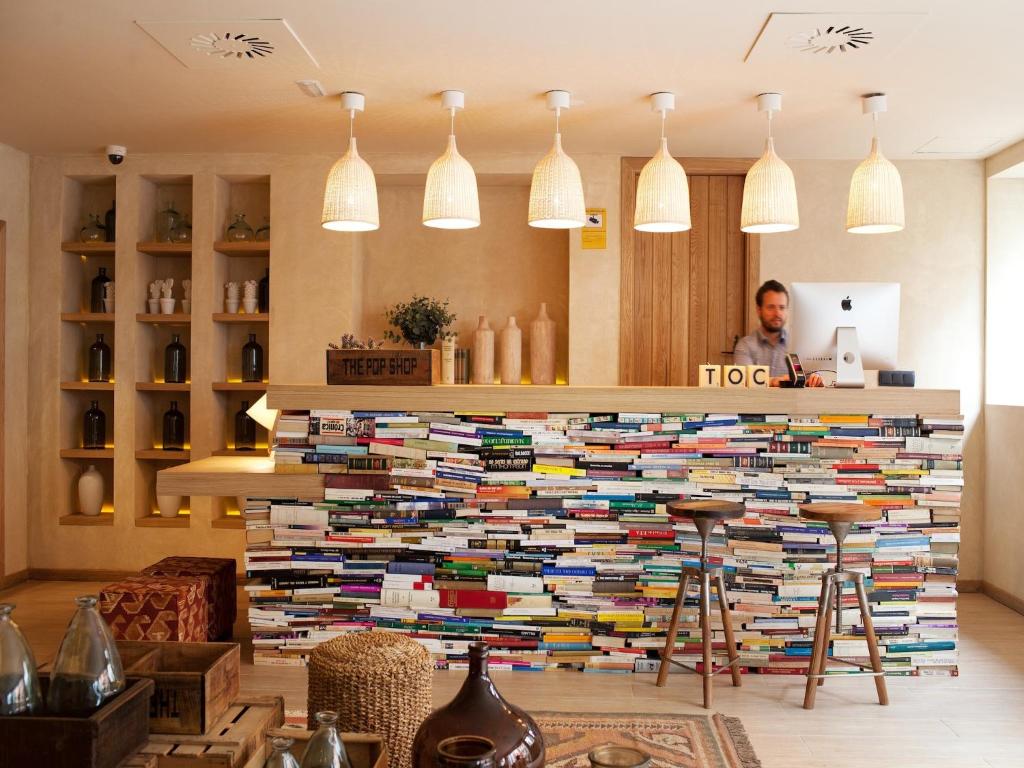 een man staat achter een grote stapel boeken bij Toc Hostel Sevilla in Sevilla