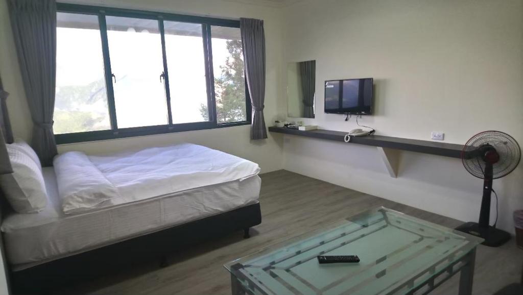 a room with a bed and a tv and a window at 清境宿霧山宛 in Ren&#39;ai